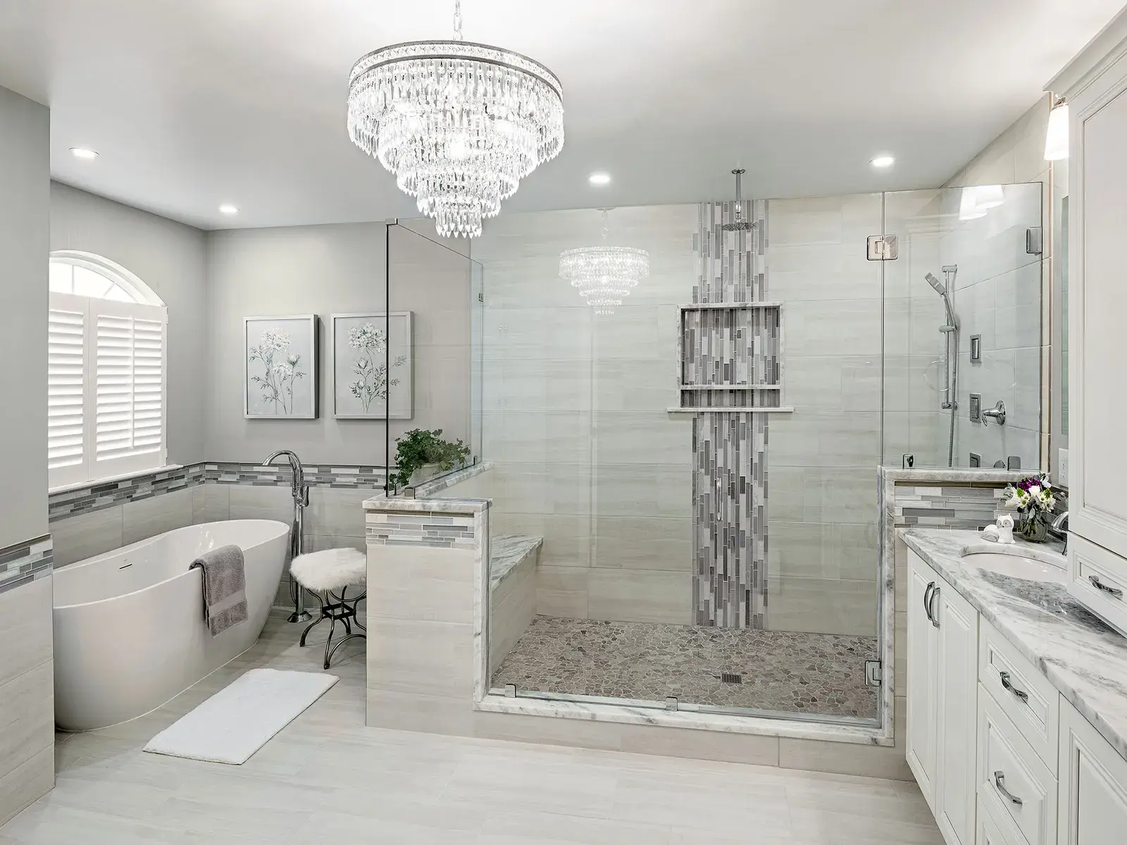 Walk-in shower with a linear mosaic band, freestanding tub and chandelier