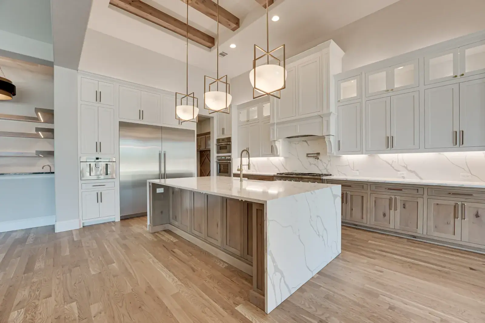 Kitchen remodel with white shaker cabinets, a wood island, a veined stone island top and a full-height stone backsplash