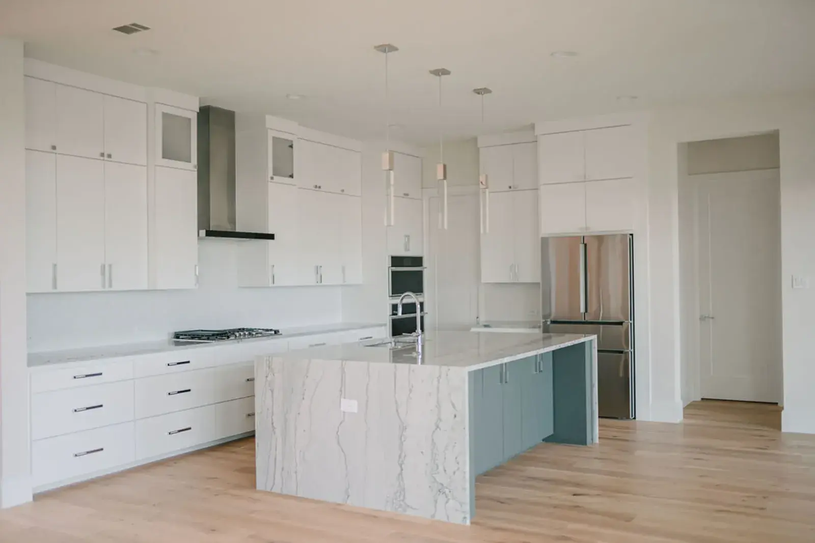 Kitchen with white cabinets, a waterfall-edge island and wide-plank wood floor