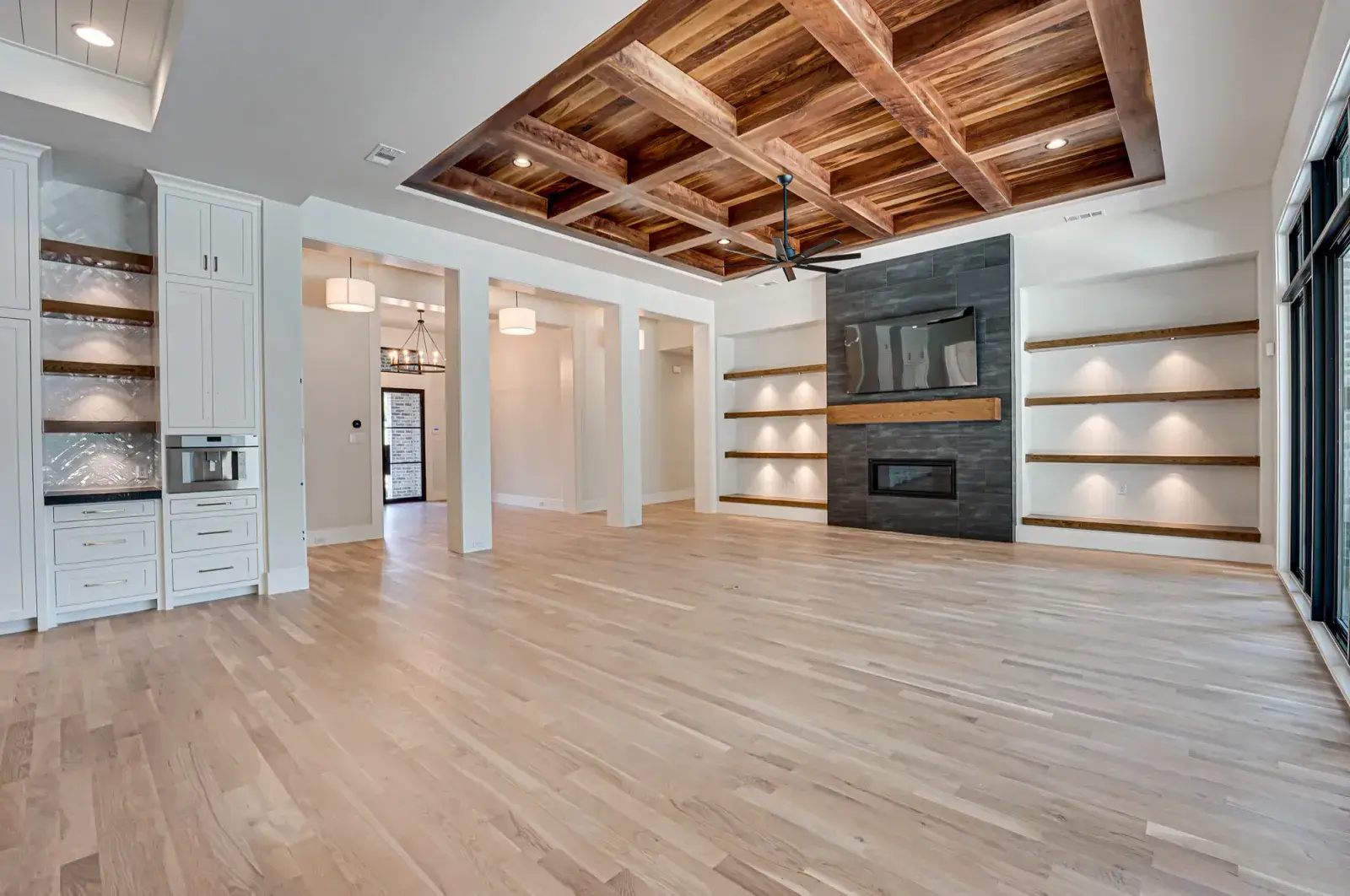 Living room with wide-plank oak floor, coffered wood ceiling and built-ins around the fireplace