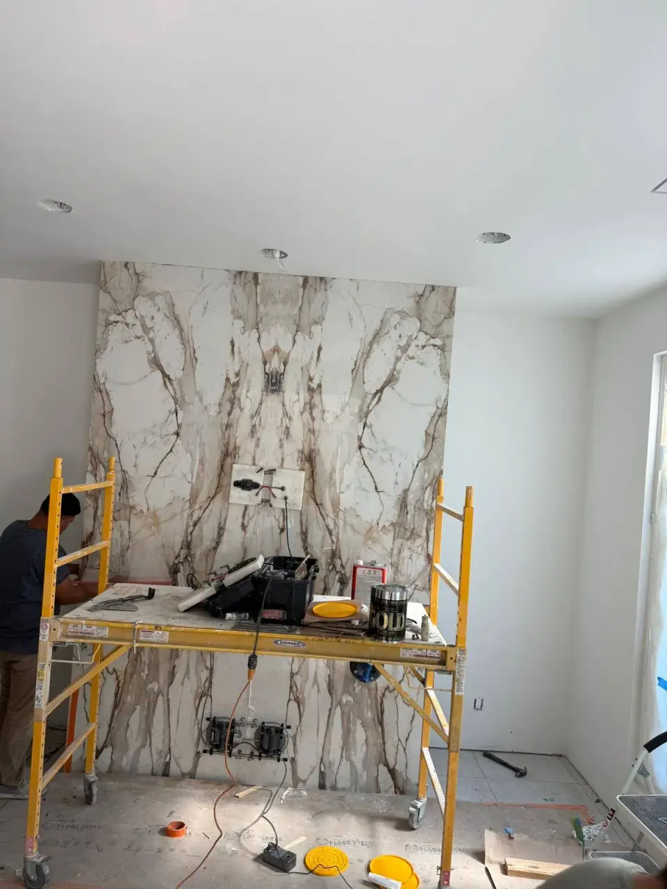 Bookmatched slab wall being set from scaffolding