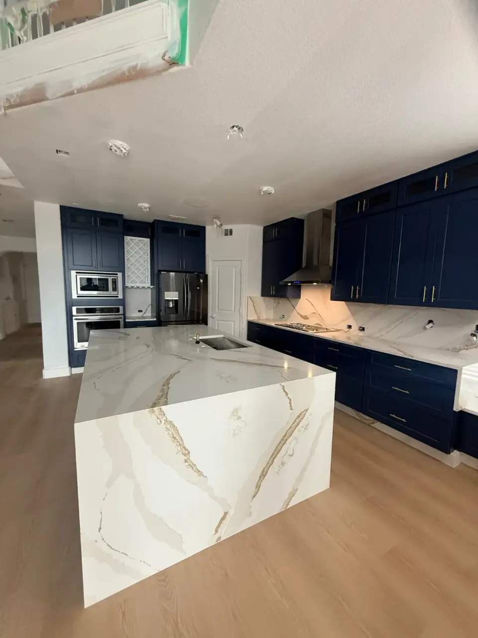 Kitchen with navy cabinets and a gold-veined waterfall island
